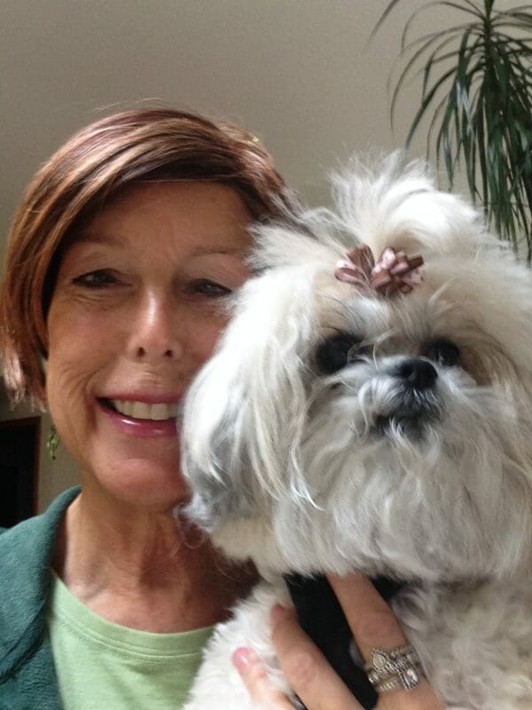 Shoo with a small white dog smiling at the camera.